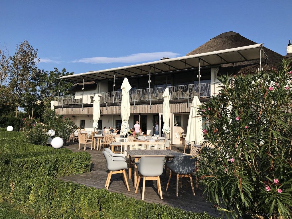 einstoeckiges Haus mit Terrasse mit Tischen und Schirmen