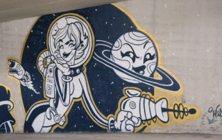 Streetart mit Cartoon im Graffitipolis in Mulhouse von einer Astronautin und einer Sonne mit Gesicht