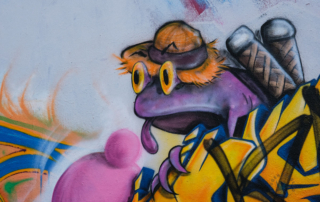 Ausschnitt eines Murals mit violettem Frosch mit Sonnenhut und heraushängender Zunge