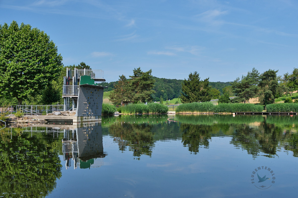 See mit Sprungturm, Kletterwand und Wiese